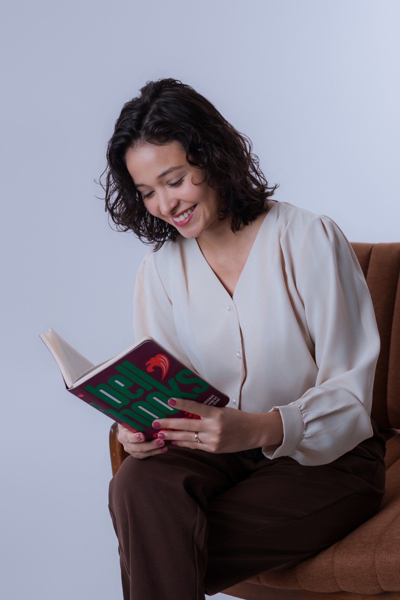 Michelle Guimarães sorrindo enquanto lê um livro de bell hooks