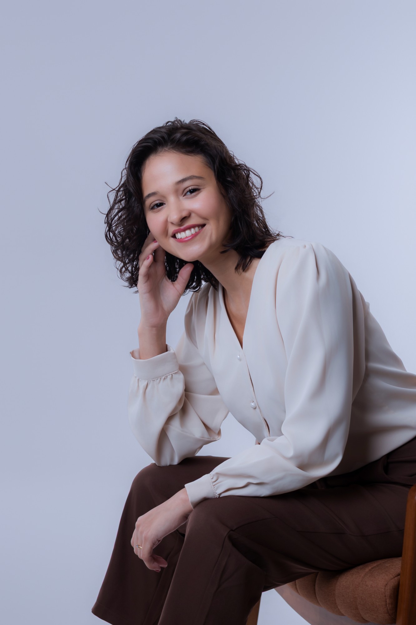 Michelle sentada, sorrindo, com a mão no rosto